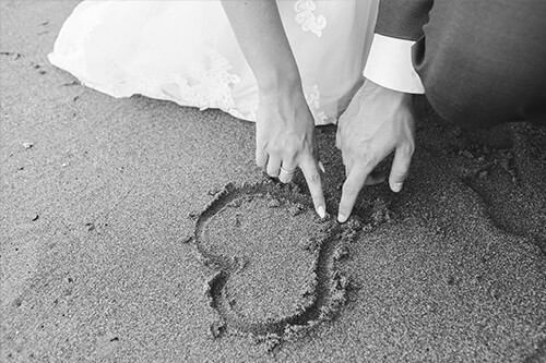 Bride and Groom Drawing Heart in Sand